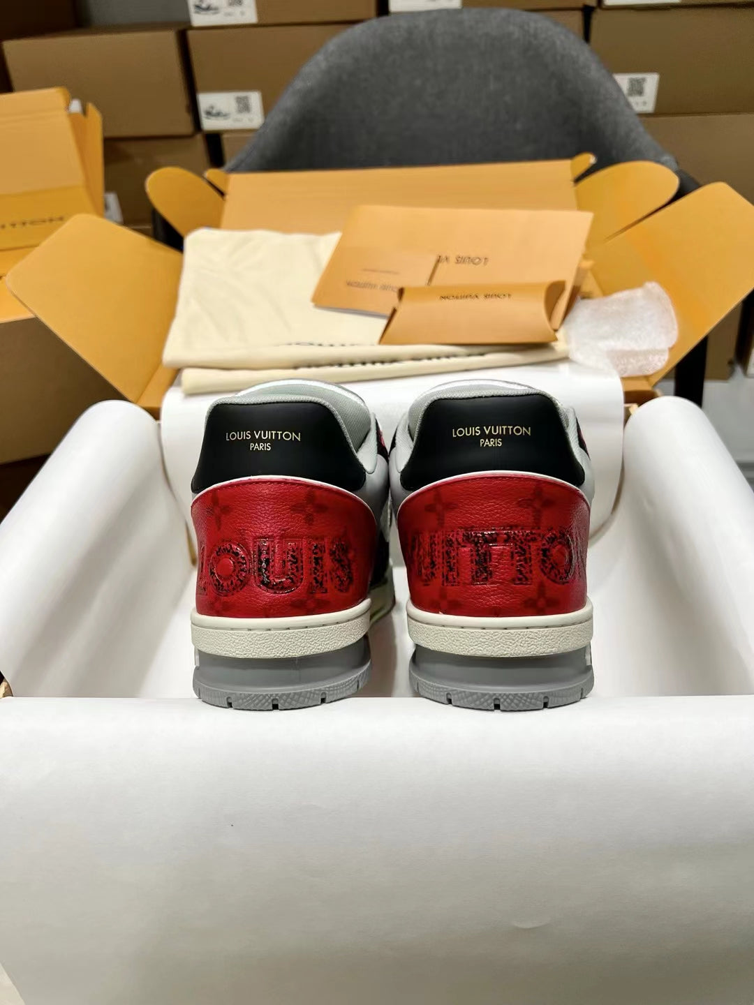 Back view of black and white sneakers with red textured heel and gray soles