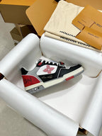Black and white sneaker with red heel and logo patch, lace-up style