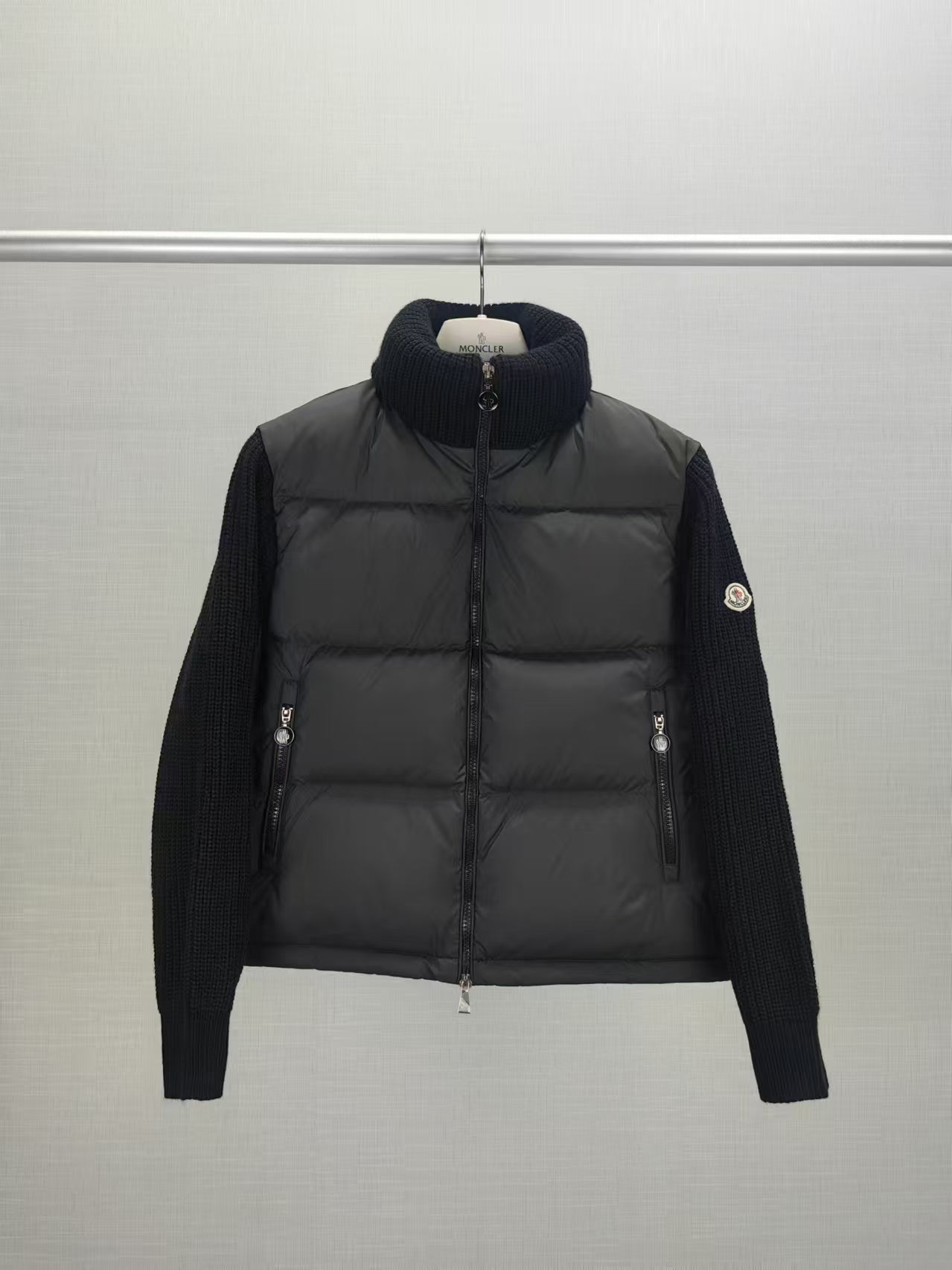 Long puffer jacket with knit sleeves, dark collar, front zip closure and pocket zips