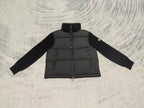 Long puffer jacket front view with knit sleeves, stand collar, visible front zipper