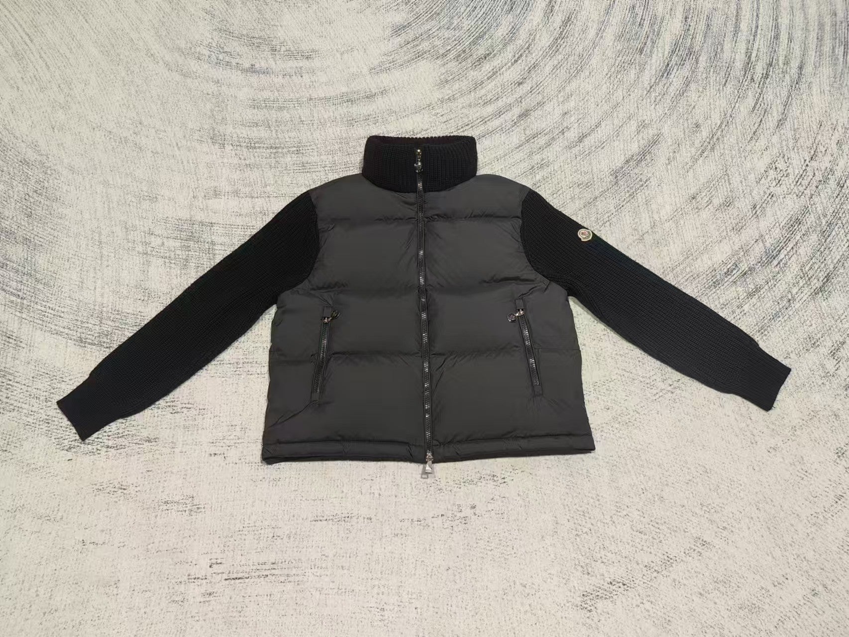 Long puffer jacket front view with knit sleeves, stand collar, visible front zipper