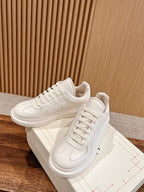White lace-up sneakers with stitched accents, pair shown with matching box