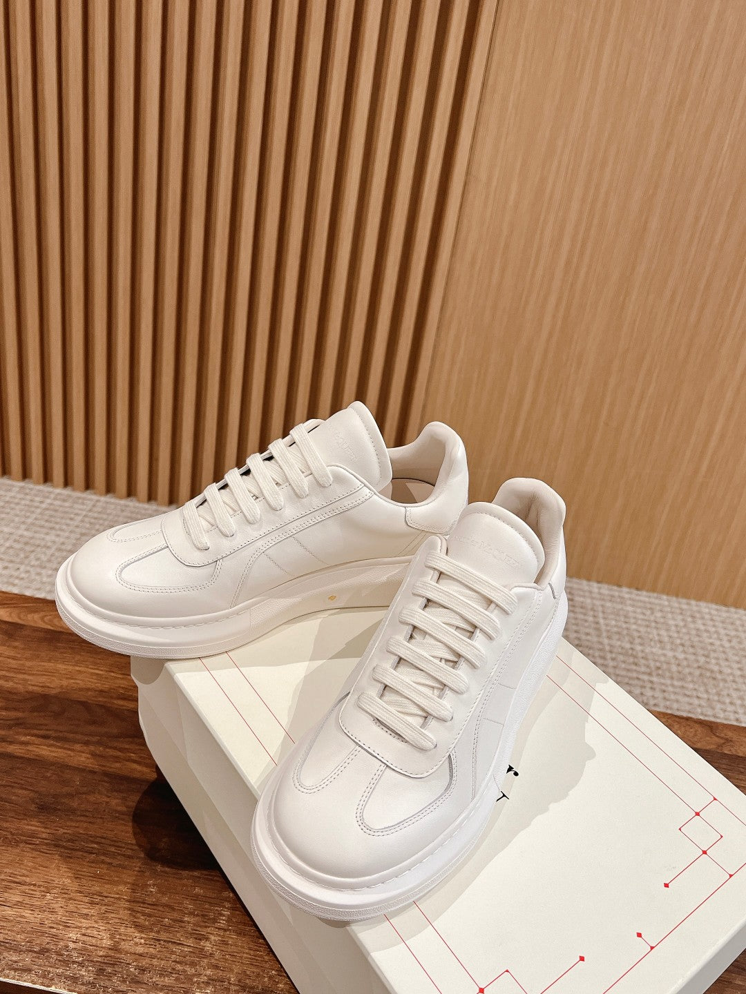 White lace-up sneakers with stitched accents, pair shown with matching box