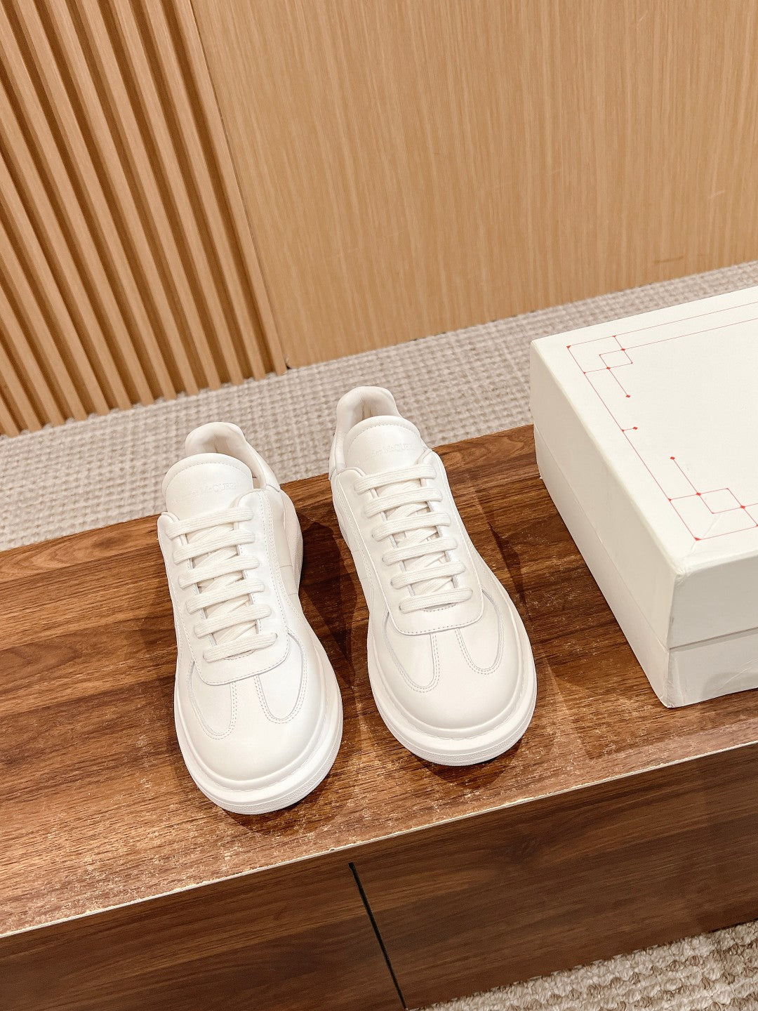 White lace-up sneakers pair with low sole and stitched swoop accents