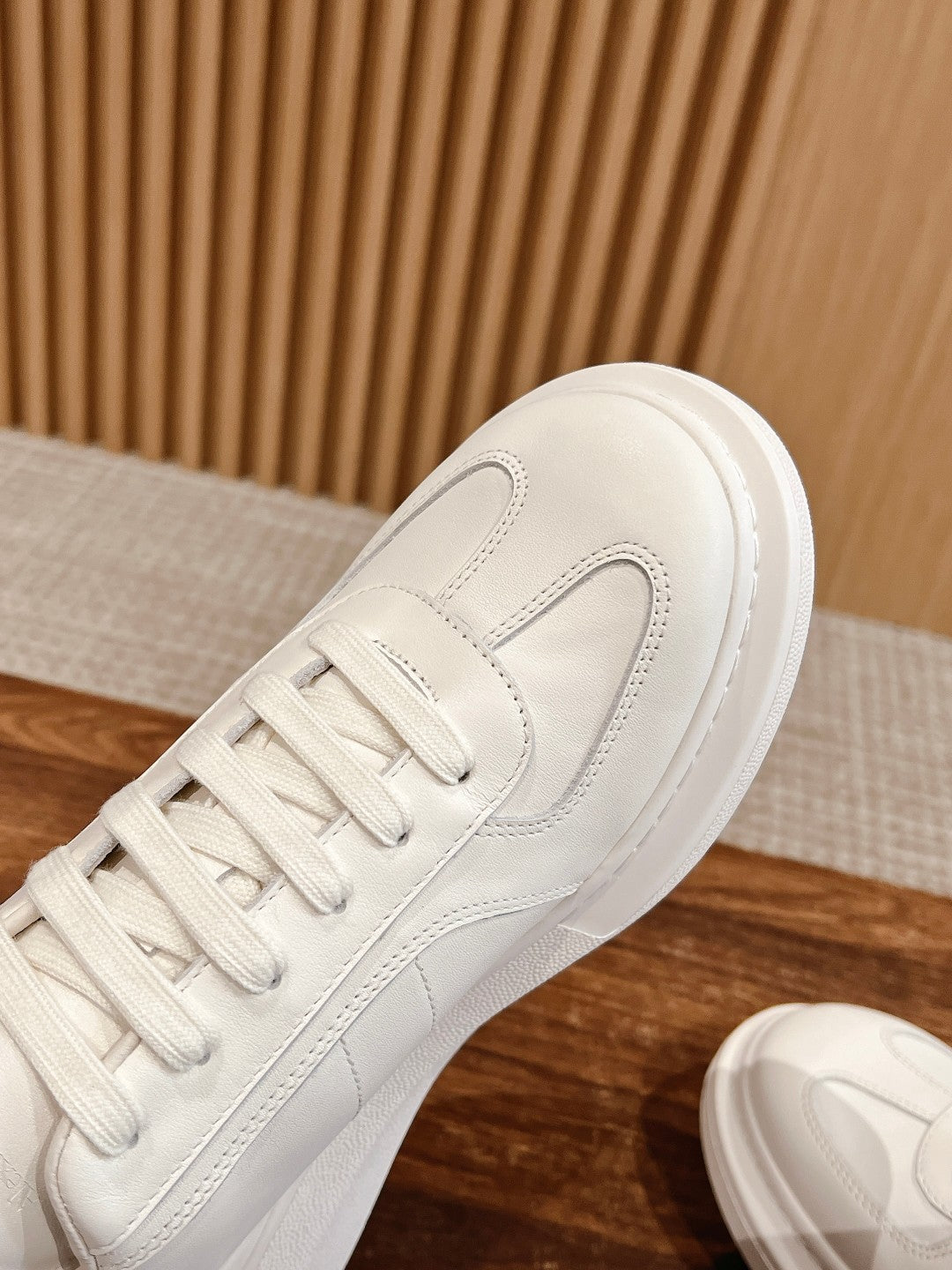 White leather sneaker side view with lace-up front and stitched panel edges