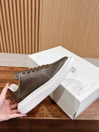 Dark gray leather low-top sneaker with white sole and brown lace-up front