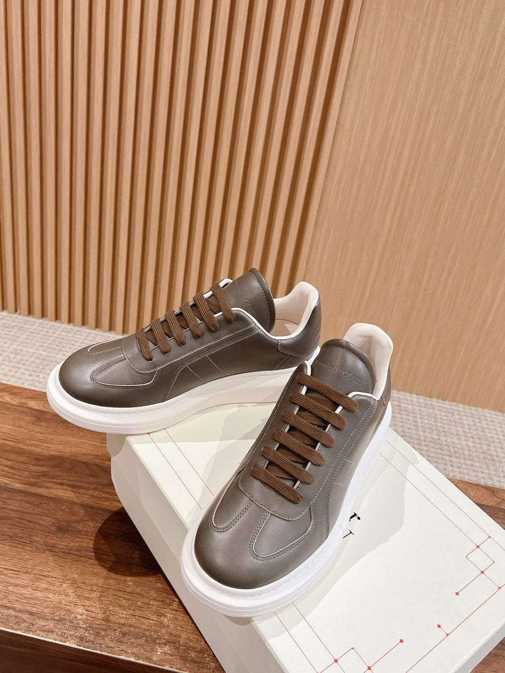 Two dark gray leather low-top sneakers with white soles and brown lace-up uppers