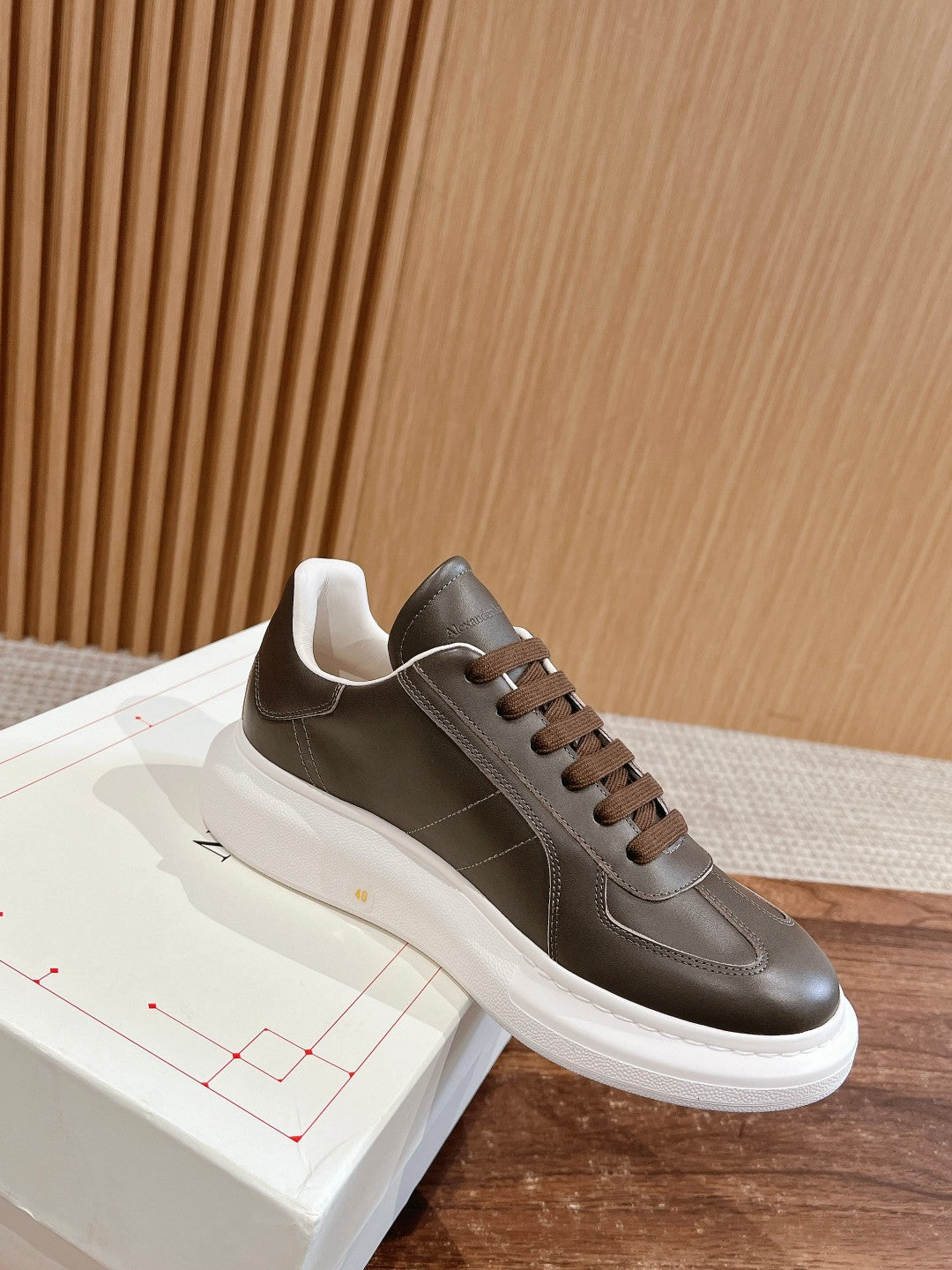 Dark gray leather low-top sneaker with white sole, brown laces, and side stitching
