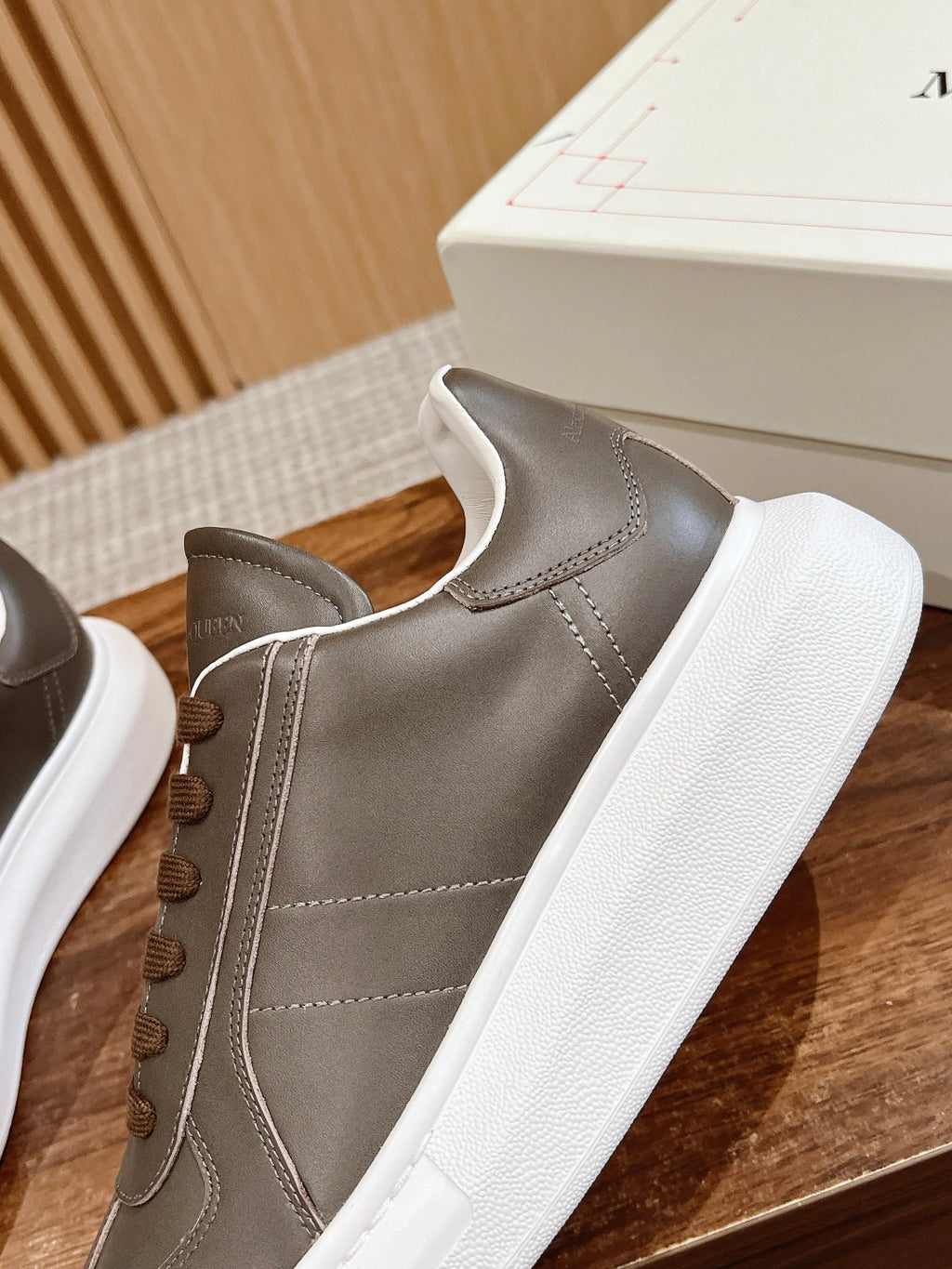 Close-up of dark gray leather low-top sneaker with white sole and brown laces