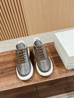 Pair of dark gray leather low-top sneakers with white soles and brown laces