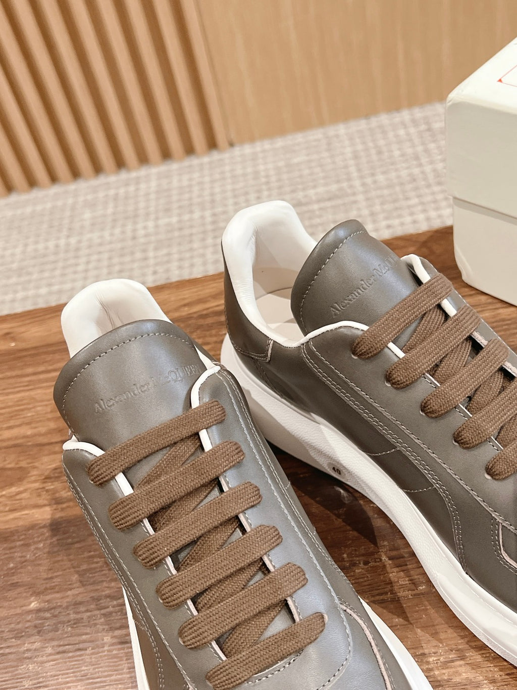 Pair of dark gray leather sneakers with white midsoles and brown lace-up panels