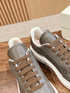 Pair of dark gray leather sneakers with white midsoles and brown lace-up panels