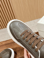Side view of dark gray leather low-top sneaker with white sole and brown laces