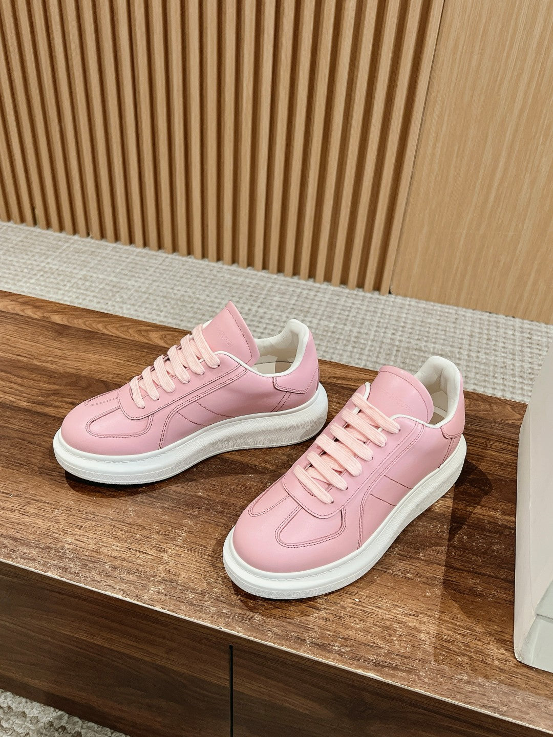 Pink low-top sneakers with stitched panels and lace-up closure on box