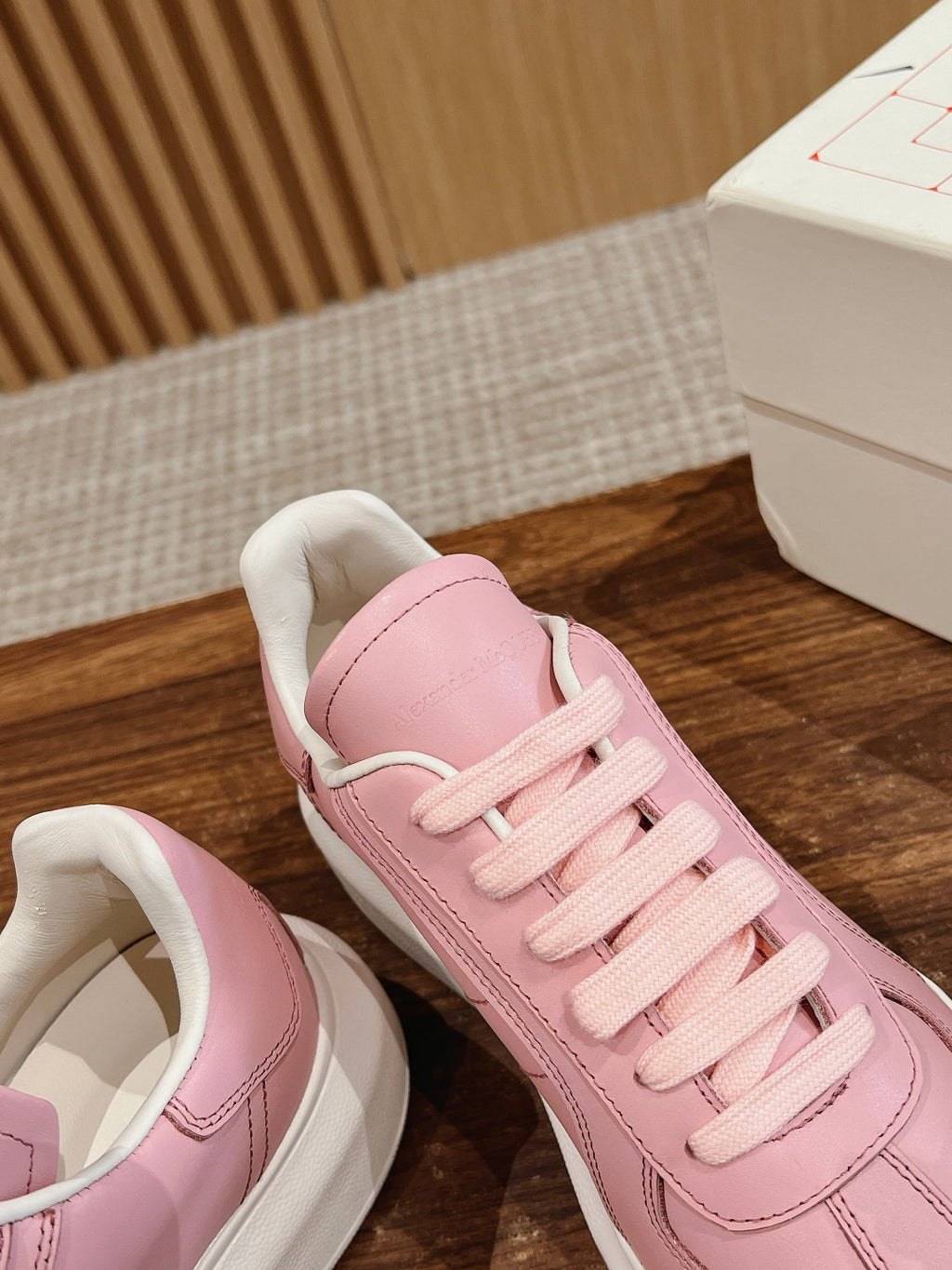 Pink sneakers with padded collar and lace-up front, angled close-up