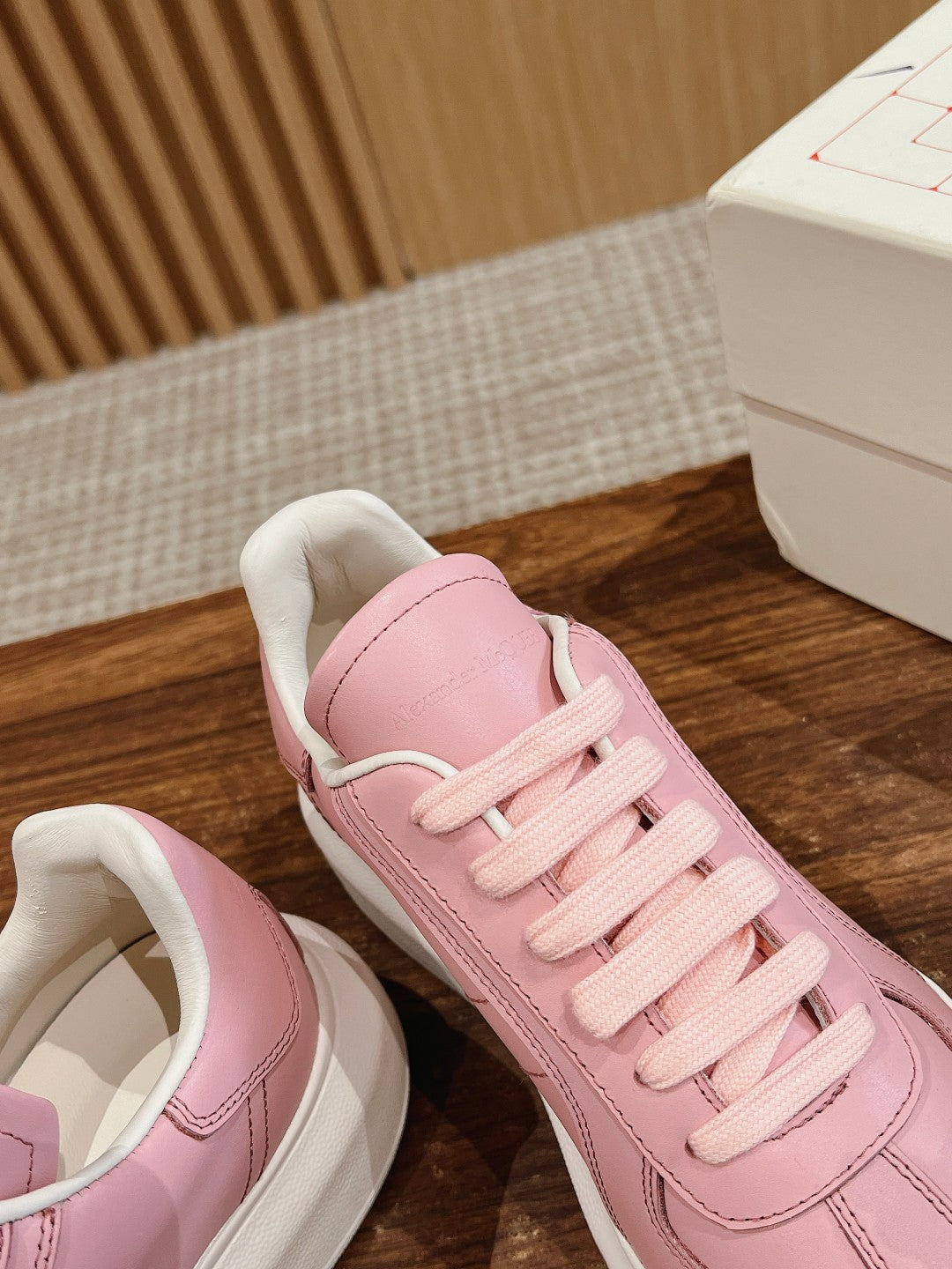 Pink sneakers with padded collar and lace-up front, angled close-up