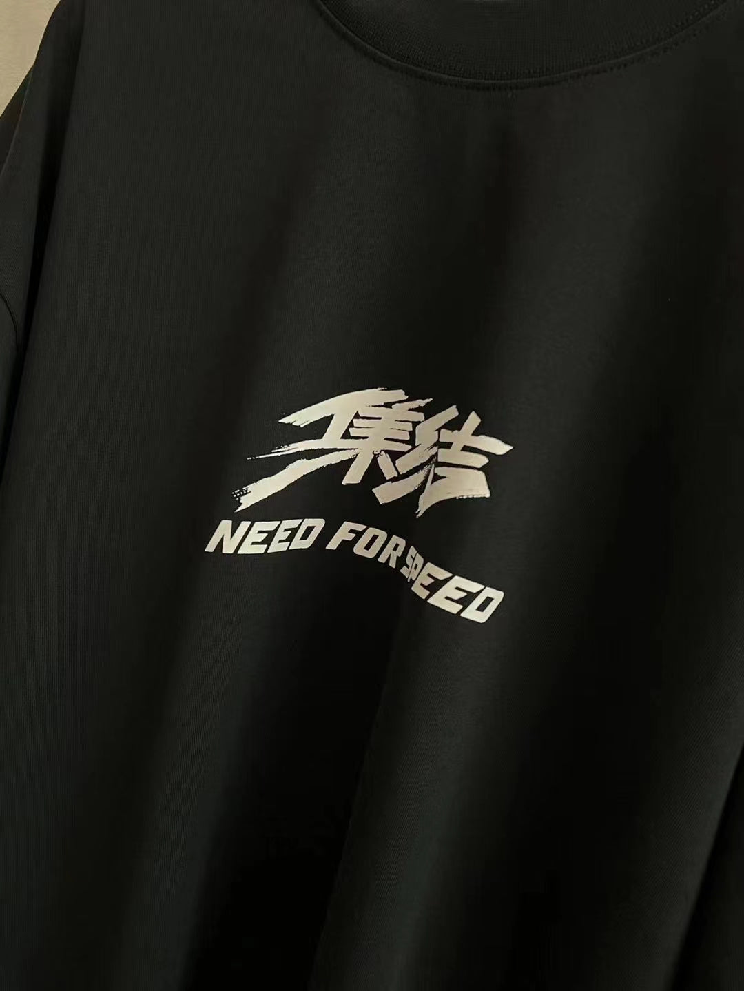 Black short-sleeve T-shirt with small white “NEED FOR SPEED” logo graphic.