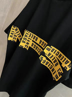 Black short-sleeve T-shirt sleeve with yellow “Need for speed” text print.