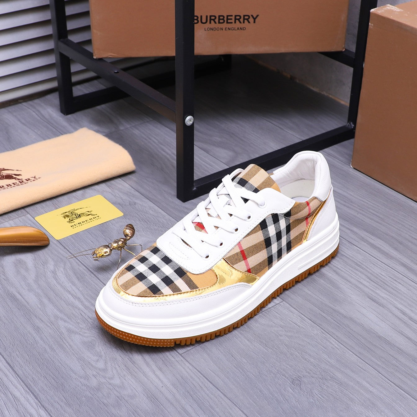 White Burberry sneakers with check panel upper, gold trim, and orange sole