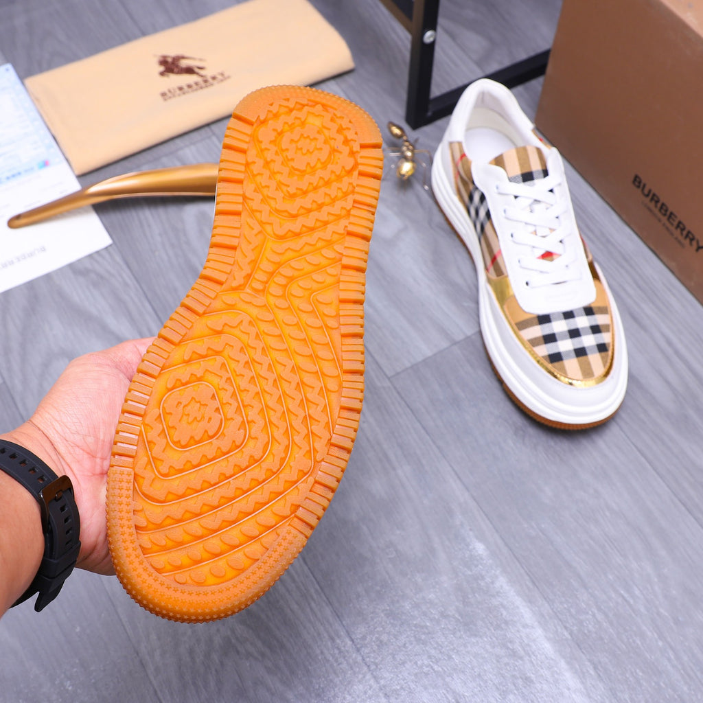 Orange rubber outsole tread of a Burberry sneaker with white check upper