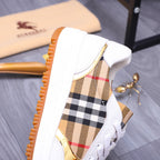 Side view of white Burberry sneaker with check panel upper and orange sole edge