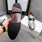 Versace loafer outsole with dark rubber tread and logo, viewed from heel side.
