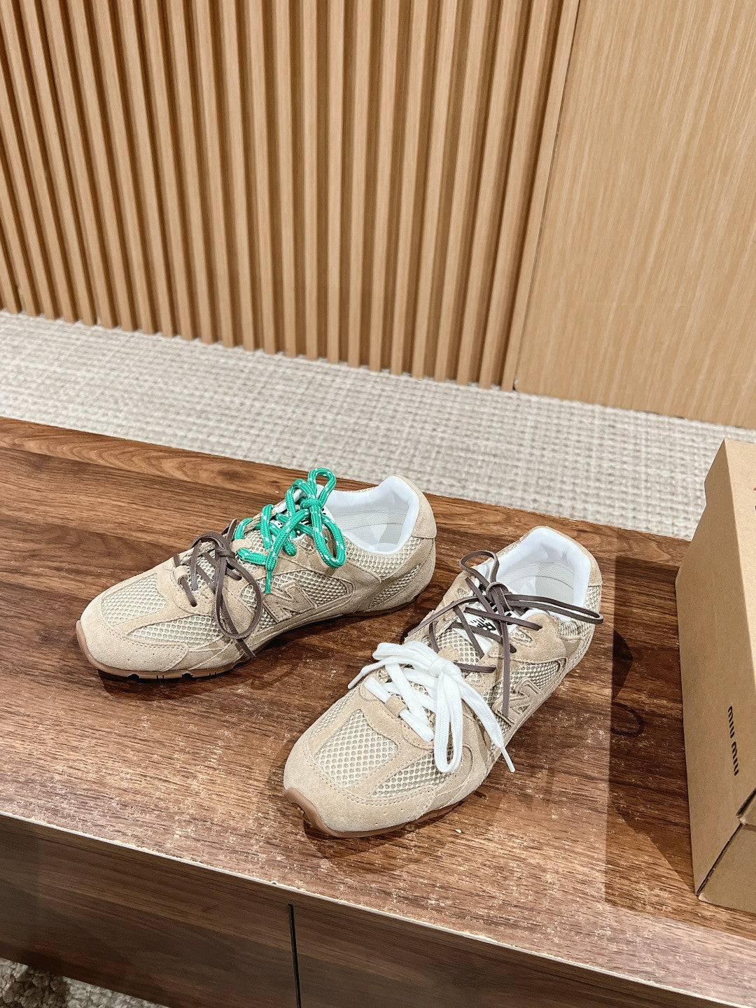 Prada unisex sneakers on display, beige mesh uppers with teal laces and white laces