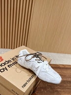 White low-top sneakers on New Balance shoebox, lace-up front