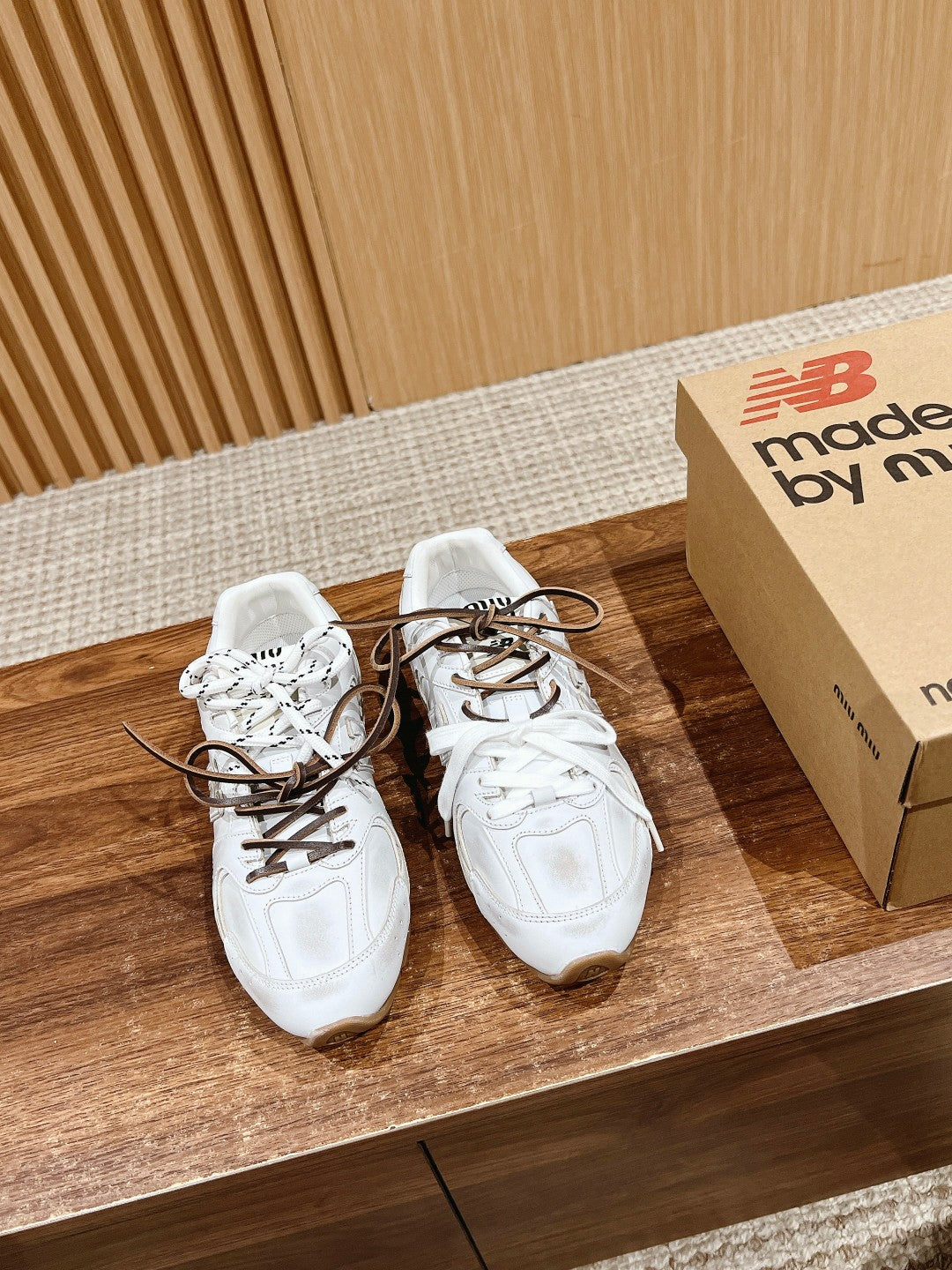 White low-top sneakers, brown lace-up, on wooden shelf