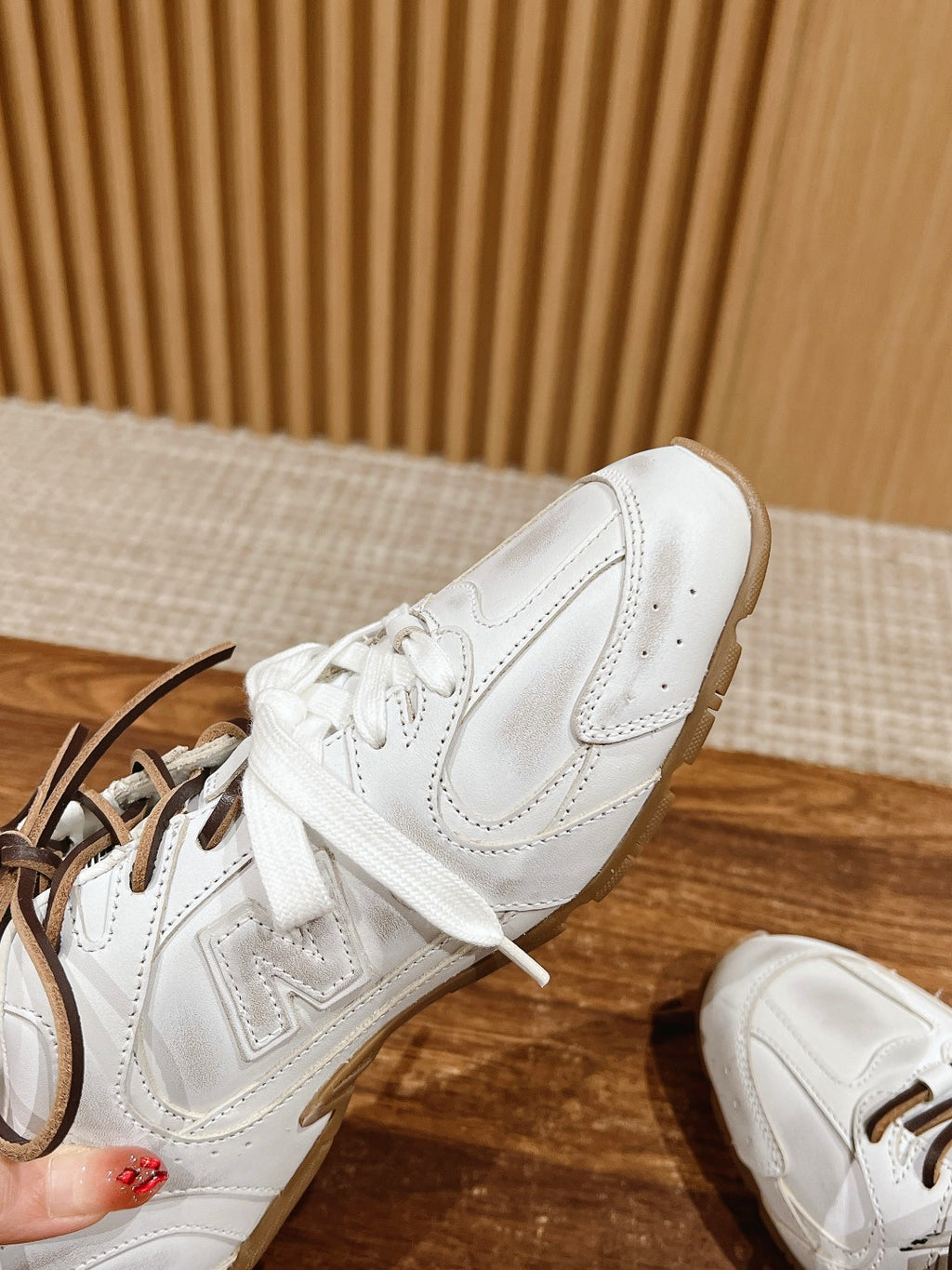 Close-up of white low-top sneakers with brown laces, side and toe details