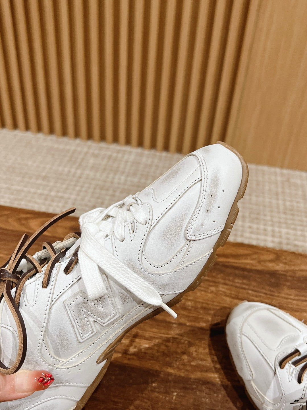 Close-up of white low-top sneakers with brown laces, side and toe details