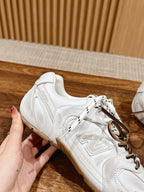 Hand holding white low-top sneaker showing side panel stitching and laces