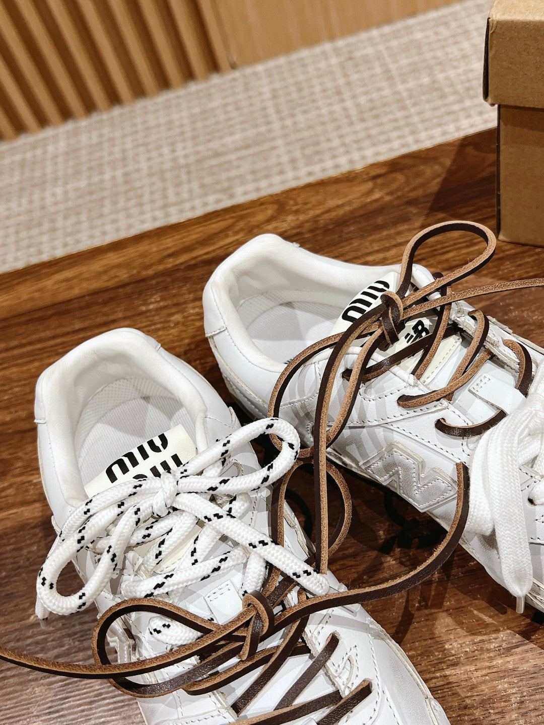 Pair of white low-top sneakers with brown laces, top view
