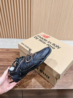 Black unisex sneakers with white laces and low-profile soles, hand-held