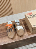 Brown suede sneakers with orange and black laces, white inner lining, lace tag.