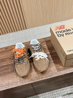 Brown suede sneakers with orange and black laces, white inner lining, lace tag.