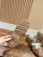 Brown suede sneakers outsole and heel tread view, white tongue and laces visible.