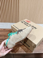 Unisex suede sneakers with green laces on brown shoebox; left shoe lifted
