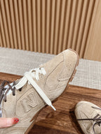 Unisex suede sneakers with white laces and N logo detail, one shoe held