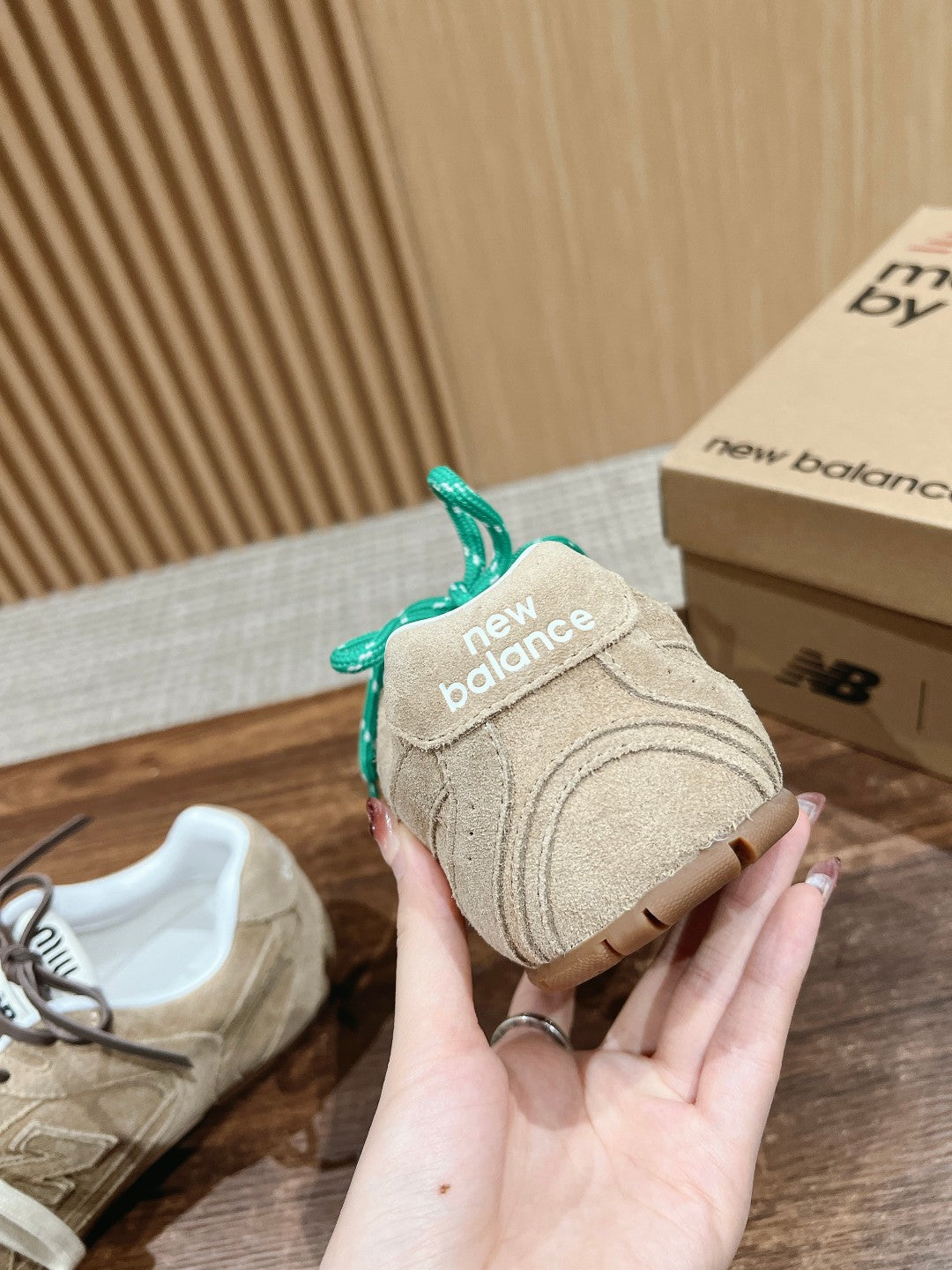 Unisex suede sneakers with green laces, New Balance logo detail, hand-held