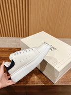 White leather low-top sneaker with navy heel tab, lace-up and perforated toe