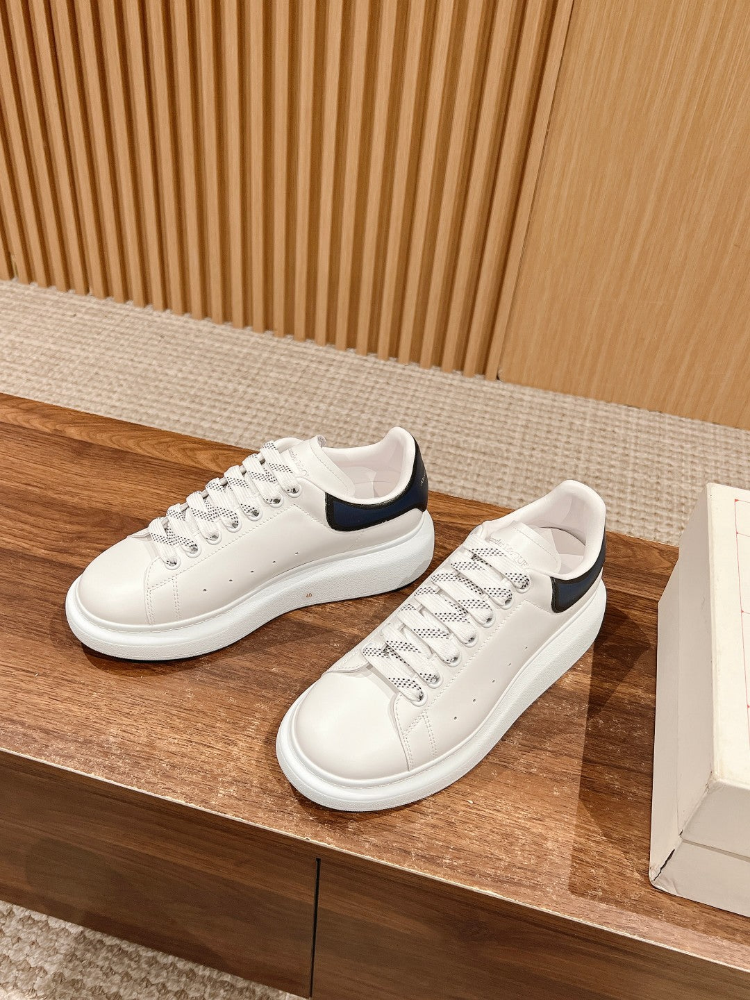 White leather lace-up sneakers with navy heel tabs and perforated toe
