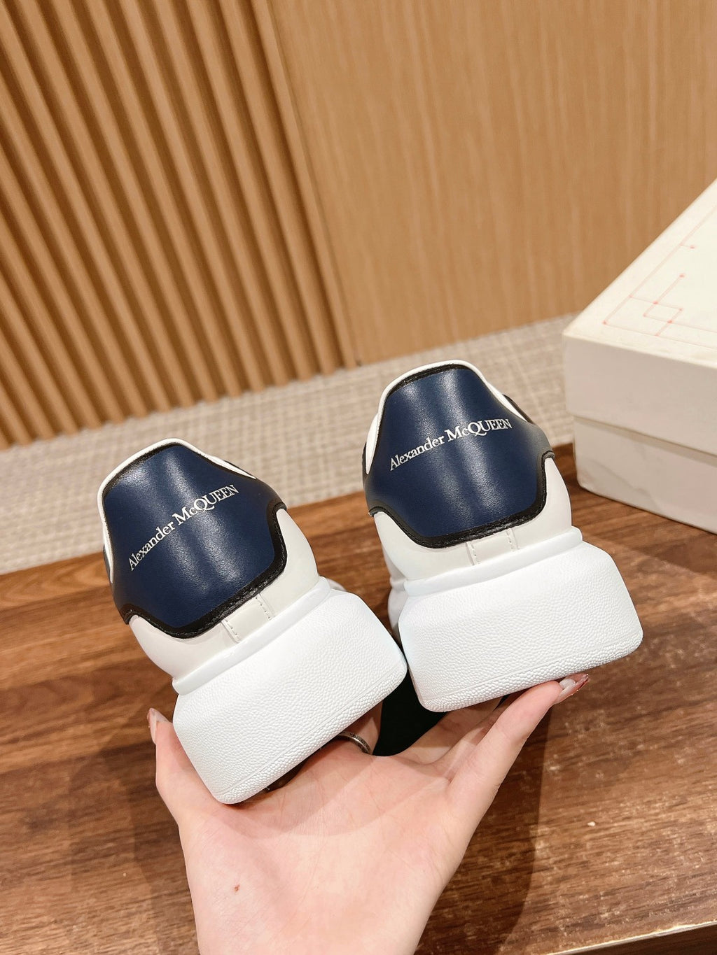 Alexander McQueen sneakers with white uppers and navy heel tabs, side-by-side