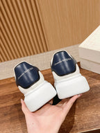 Alexander McQueen sneakers with white uppers and navy heel tabs, side-by-side