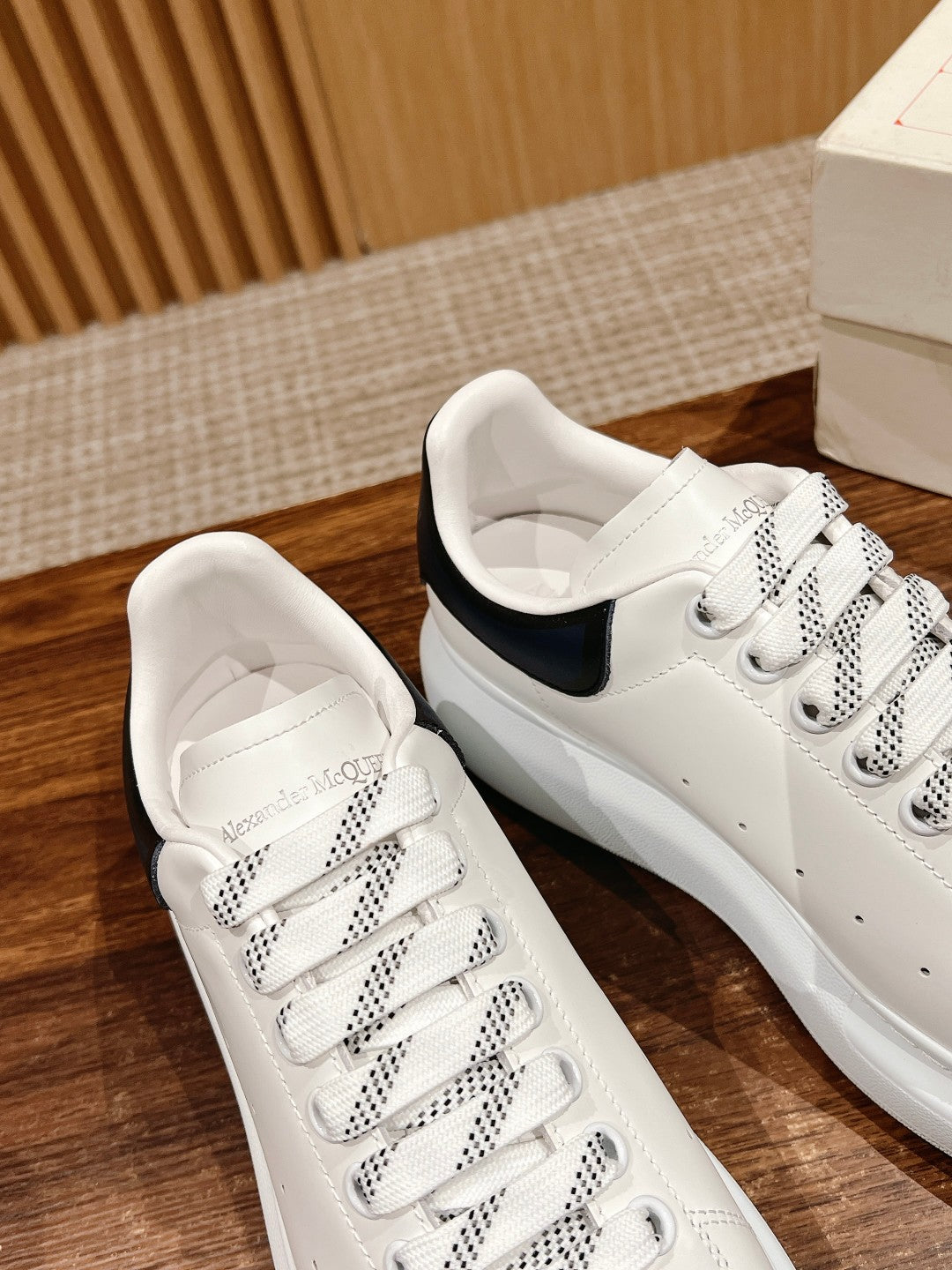 White leather lace-up sneakers with navy heel tab, side view with box