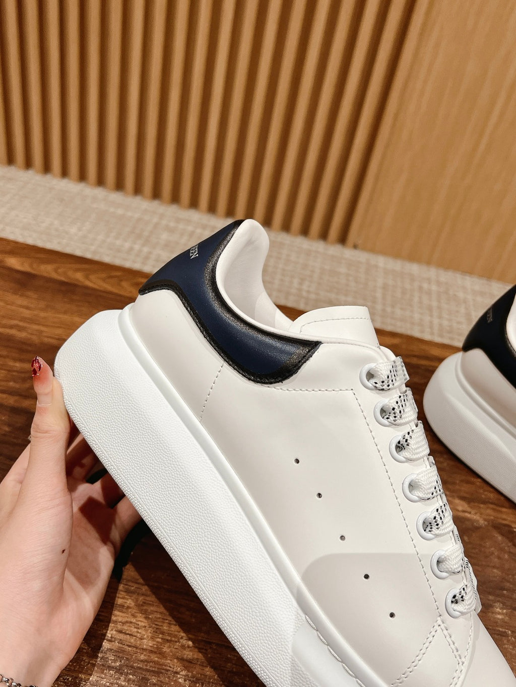 White sneaker with navy collar trim, thick sole, and lace-up front
