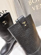 Close-up of black mid-calf boots with embossed FENDI-style texture and gold plaque
