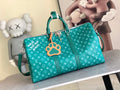 Teal monogram duffel bag with top handles, shoulder strap, and paw-shaped charm