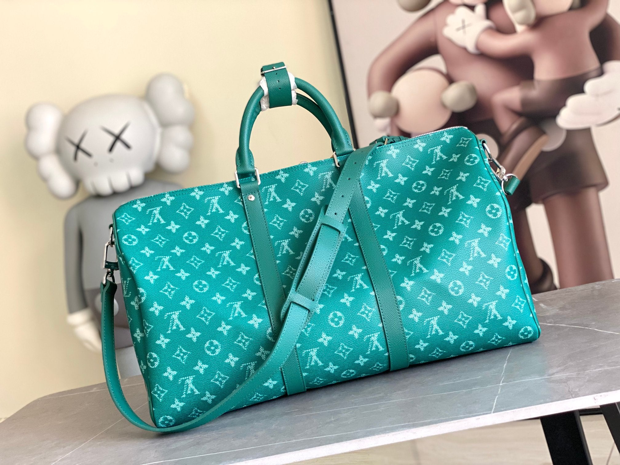Teal monogram duffel bag with front straps, top handles, and side shoulder strap