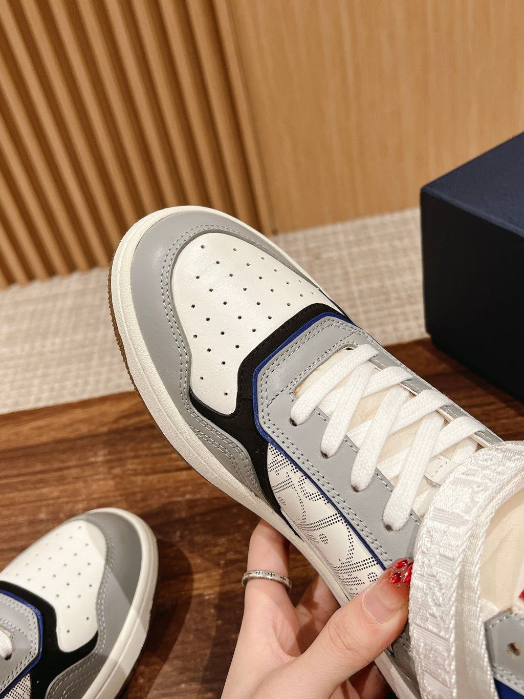 Unisex sneaker side view, white upper with blue stripe and perforated toe
